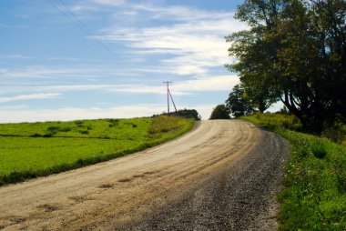 Dirt road in countryside on blue sky