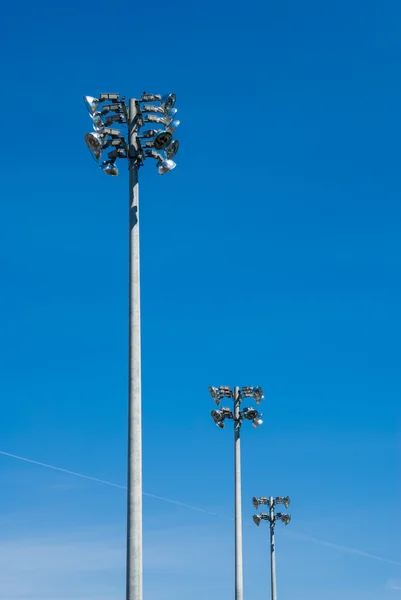 Row of stadium flood light towers on blue sky. — Stock Photo, Image
