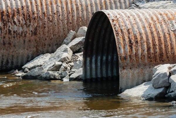 Rusted culvert pipe opening in water. — Stock Photo, Image