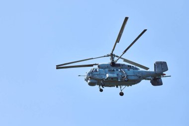 Donanma helikopteri parlak mavi gökyüzü arka planına doğru uçuyor, anlaşıldı. Denizaltı savaş karşıtı bir askeri helikopter denizaltı araması yapıyor.