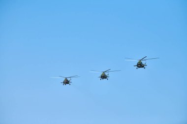 Gösteri uçuşunu gerçekleştirirken mavi gökyüzünde uçan üç askeri helikopter, kopyalama uzayı. Aerobatik takım hava gösterisinde uçuyor.