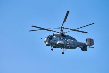 Donanma helikopteri açık mavi gökyüzü arka planına doğru uçuyor, anlaşıldı. Gösteriler sırasında uçan bir döner kanat uçağı, yan görünüm