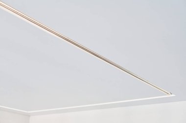 Dairede ya da evde boş bir odada asılı duran, kare LED lambalı asılmış tavan. Mat taneli desenli beyaz germe tavanı. Ev yenileme, tadilat.