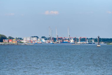Lojistik ihracat ve ithalatta konteyner gemisi terminali. Kargoyu limana vinçle, mavi gökyüzüyle ve denizle, gündüz. Yük taşımacılığı, dünya çapında taşımacılık, lojistik, küresel iletişim, endüstri