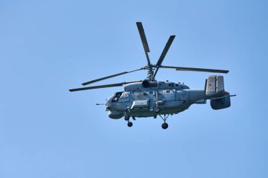 Donanma helikopteri açık mavi gökyüzü arka planına doğru uçuyor, anlaşıldı. Gösteriler sırasında uçan bir döner kanat uçağı, yan görünüm