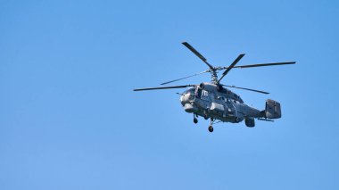 Donanma helikopteri açık mavi gökyüzü arka planına doğru uçuyor, anlaşıldı. Gösteriler sırasında uçan bir döner kanat uçağı, yan görünüm