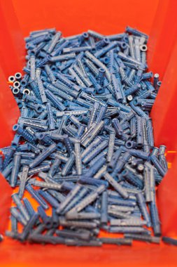 Dowels duvar tıkaçları kapanıyor. Kırmızı arka planda plastik mavi paneller, fiksasyon ve montaj için perdeler ve çeşitli duvar malzemeleri, beton ve ahşap. Tamirat ve tamirat için aksesuarlar