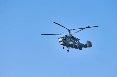 Donanma helikopteri açık mavi gökyüzü arka planına doğru uçuyor, anlaşıldı. Gösteriler sırasında uçan bir döner kanat uçağı, yan görünüm