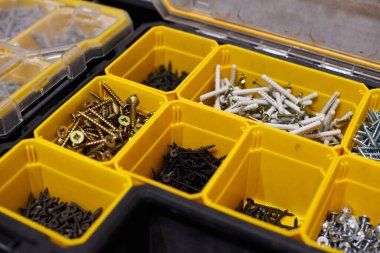 Küçük inşaat eşyalarıyla dolu sarı bir çanta. Vidalar, somunlar, civatalar, çiviler ve diğer aletleri atölyede bulunan inşaatçılarla dolu birçok depo kompartımanı. Düzenli ve düzenli.