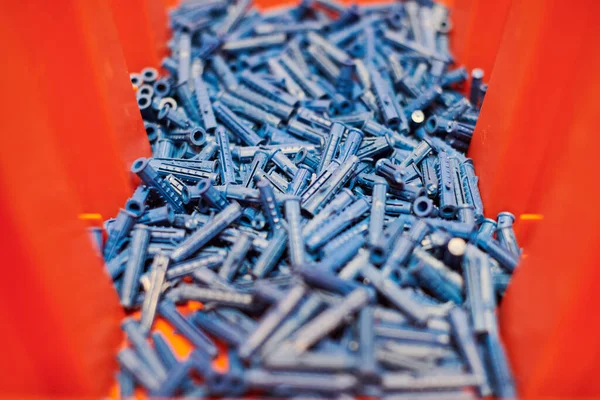 Dowels wall plugs close up. Plastic blue dowels on red background, dowels for fixation and installation and various wall materials, concrete and wood. Accessories for repairing and handymen