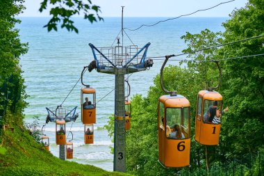 Svetlogorsk, Rusya - 08.14.2021 - Yeşil dağdan Cableway. Sarı arabalı Svetlogorsk teleferiği. Turistler için Baltık Denizi sahiline hızlı hava taşımacılığı