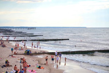 Zelenogradsk, Rusya - 07.30. 2021 - Turistlerle dolu umumi kumlu plaj. Baltık Denizi kıyısında yaz turizm sezonu. İnsanlar plajda dinleniyor ve ılık mavi denizde yüzüyorlar.