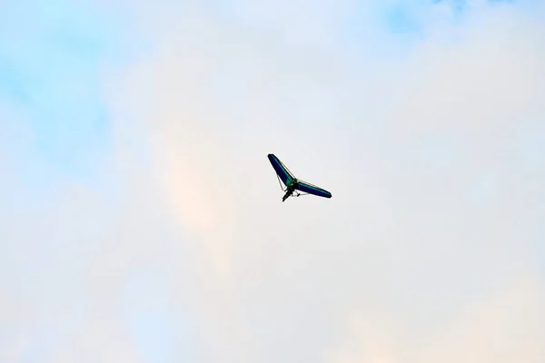 Powered hang glider flying in blue sky, motorized hang glider, ultralight trike overhead view, copy space. Tourist flight on foot-launched powered hang glider. Extreme tourism, extreme sports concept