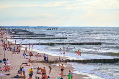 Zelenogradsk, Rusya - 07.30. 2021 - Turistlerle dolu umumi kumlu plaj. Baltık Denizi kıyısında yaz turizm sezonu. İnsanlar plajda dinleniyor ve ılık mavi denizde yüzüyorlar.