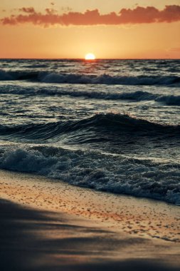 Deniz dalgaları üzerinde güzel bir gün batımı, ufukta yarım güneş, deniz manzarası. Atmosferik güneş ışığında mavi deniz dalgaları gün batımında gökyüzünde sıcak yaz tatilleri denizde, inanılmaz deniz manzarası