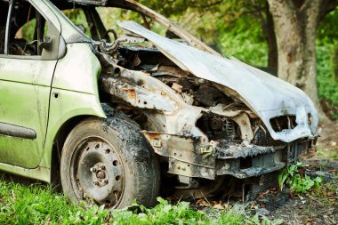 Arabanın dış tarafı yanmış, yangın çıkmış. Yanmış otomobil, araba yangını, kısa devre yüzünden araç yangını, kundaklama, duman. Hasarlı motoru ateşle