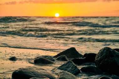 Sarı güneş neredeyse ufukta batıyor. Derin mavi denizin üzerinde. Atmosferik günbatımı gökyüzünde. Sıcak güneş ışığında güzel bir gün batımı dramatik bir gün batımı, akşam deniz manzarası