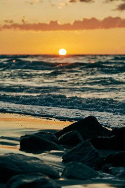Sarı güneş neredeyse ufukta batıyor. Derin mavi denizin üzerinde. Atmosferik günbatımı gökyüzünde. Sıcak güneş ışığında güzel bir gün batımı dramatik bir gün batımı, akşam deniz manzarası