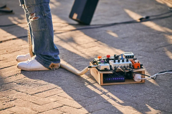 Effects pedal box for electric guitar on floor at outdoor rock party. Guitar pedalboard, effect processor with pedals near guitarist, device for alters sound of electric guitar, outdoor performance