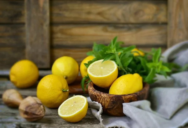 Citrons biologiques juteux et mûrs dans une menthe fraîche sur un fond en bois — Photo