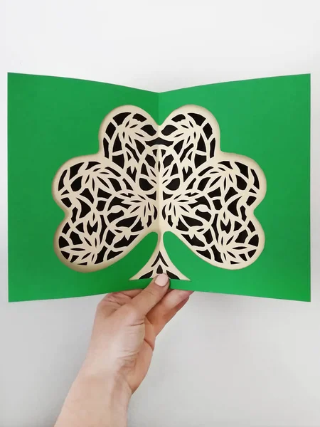 Paper cutting of green clover shamrock process, made by hand. Openwork with Irish plant leaves papercraft art, step by step workshop. Flat top view.