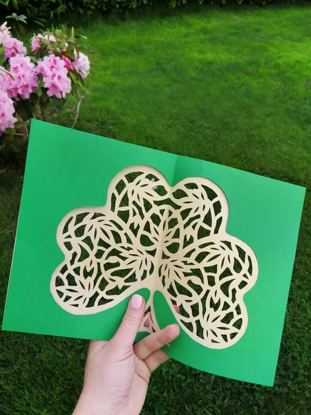 Paper cutting of green clover shamrock process, made by hand. Openwork with Irish plant leaves papercraft art, step by step workshop. Flat top view.