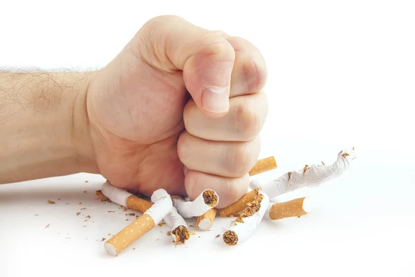 Puño humano rompiendo cigarrillos sobre fondo blanco — Foto de Stock