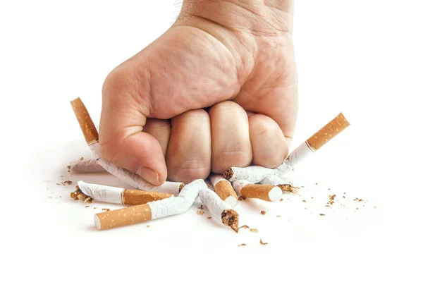 Puño humano rompiendo cigarrillos sobre fondo blanco — Foto de Stock