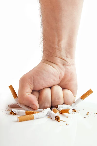 Человеческий кулак разбивает сигареты на белом фоне Стоковое Изображение