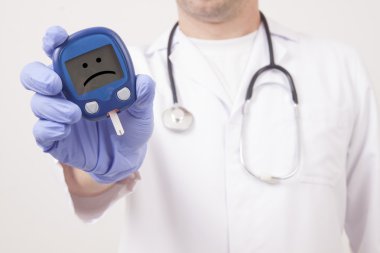 Doctor holding blood sugar meter. Sad smiley face clipart