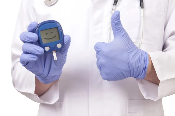 Доктор держит измеритель сахара в крови. Показан знак ОК Стоковое Изображение