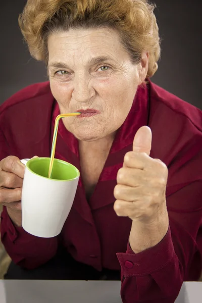 Старшая женщина пьет — стоковое фото