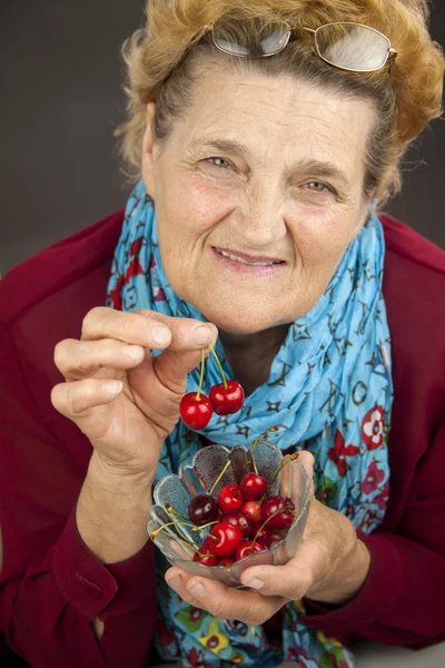 Starszy kobieta gospodarstwa wiśnie — Zdjęcie stockowe