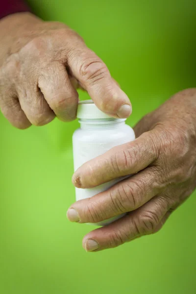 Mãos de mulher deformada de artrite reumatoide segurando garrafa — Fotografia de Stock