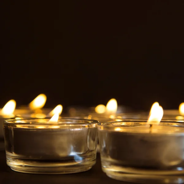 Gruppe brennender Kerzen auf schwarzem Hintergrund Stockbild