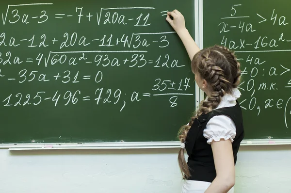 Schoolgirl at the blackboard writes — Stock Photo, Image