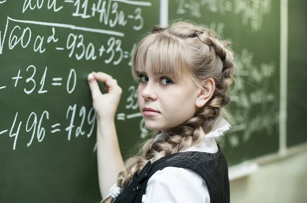 Schoolgirl at the blackboard writes — Stock Photo, Image