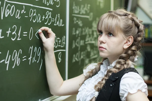 Schoolgirl at the blackboard writes — Stock Photo, Image