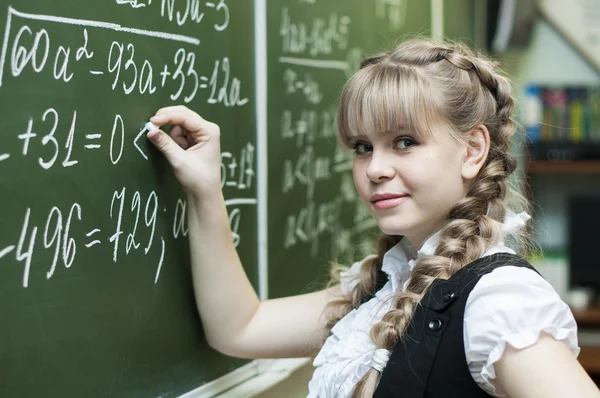 Schoolgirl at the blackboard writes — Stock Photo, Image