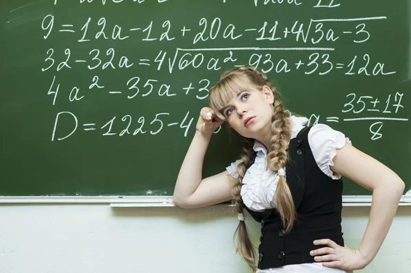 Schoolgirl at the blackboard writes — Stock Photo, Image