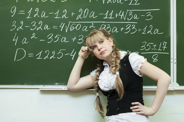 Schoolgirl at the blackboard writes — Stock Photo, Image