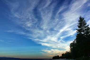 Rusya Baykal Gölü üzerinde bulutlarla güzel bir günbatımı gökyüzü. Kutsal Burun Yarımadası 'nın manzarası. Yaz. Çok renkli parlak bulutları olan güzel bir akşam gökyüzü.