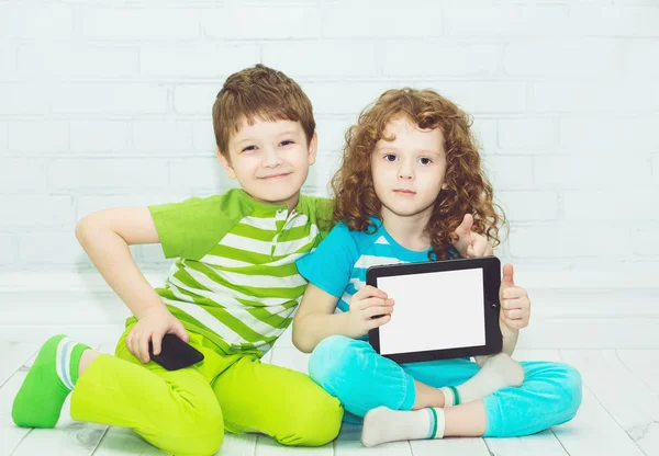 Twins boy and girls with the tablet PC on a light background. Ho