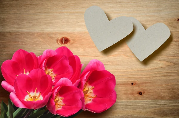 Valentine hearts and red tulips on a wooden background. — Stock Photo, Image