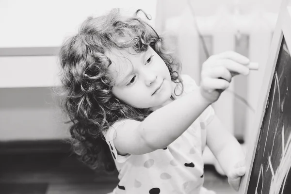 Black and white portrait of a girl writing on a chalk board.