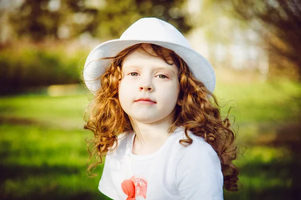 Portrait of curly girl in a white hat, toning in brown.