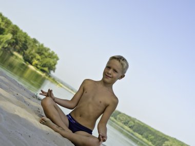 bir çocuk bir sahilde meditasyon.