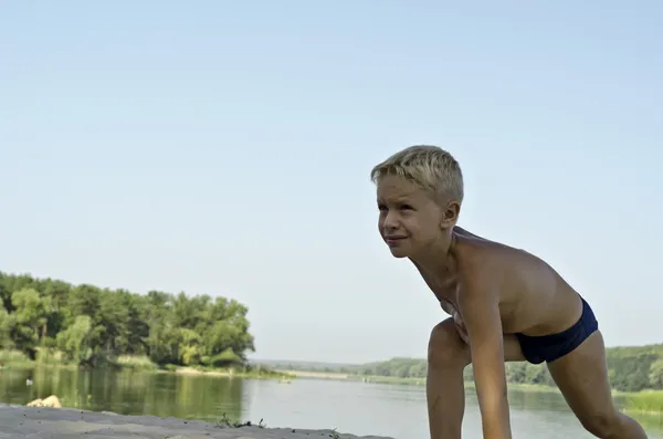 Un niño hace gimnasia en una playa . Imagen de stock