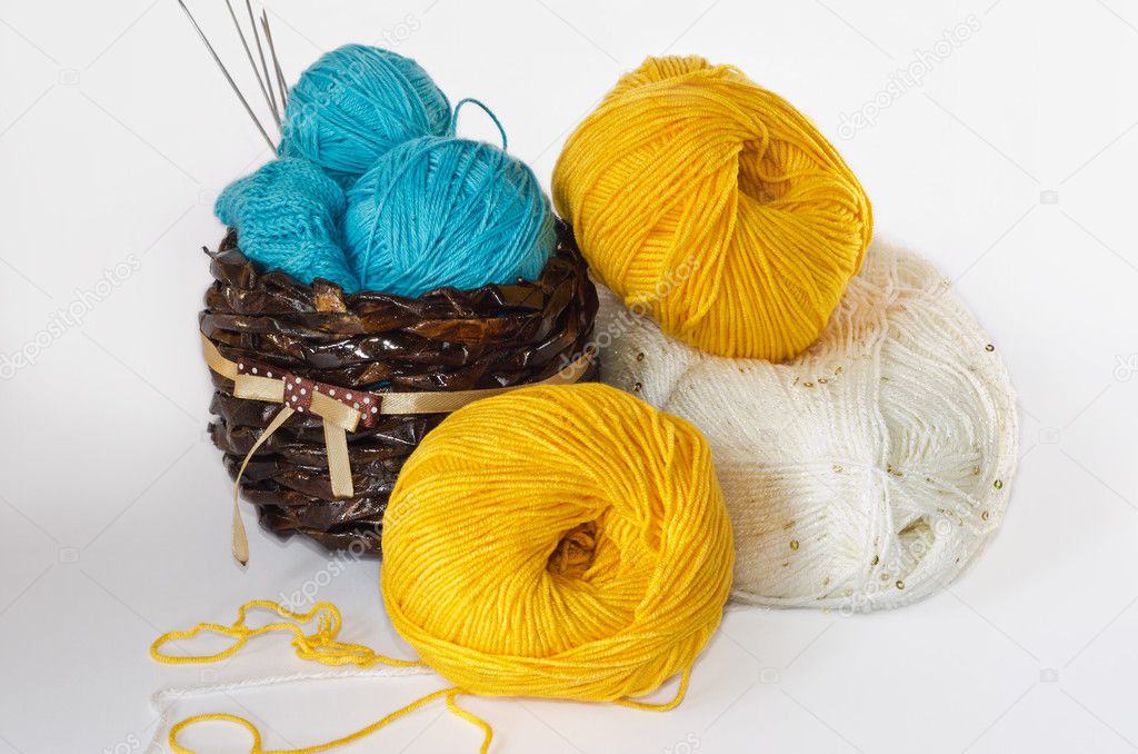 Hanks of blue, yellow, white yarn in a ped.