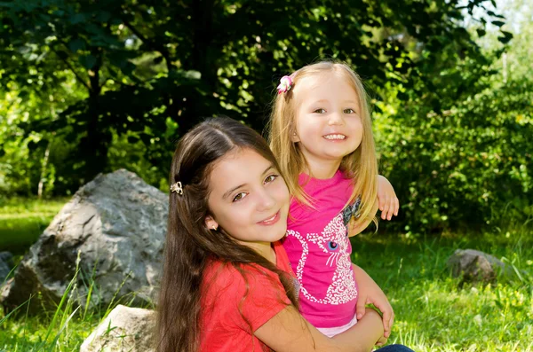 Dwie dziewczyny Zagraj w parku na trawniku wśród ogromnych kamieni. — Zdjęcie stockowe